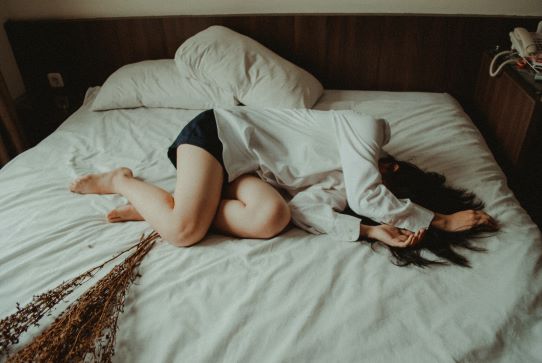 Chronic Pain Flare - image of woman curled up in pain on a bed