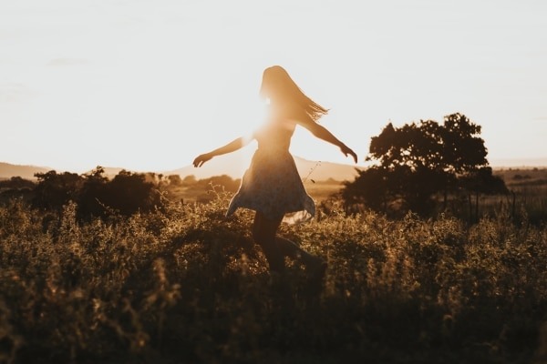 Connection between trauma and chronic pain - image of woman dancing in field